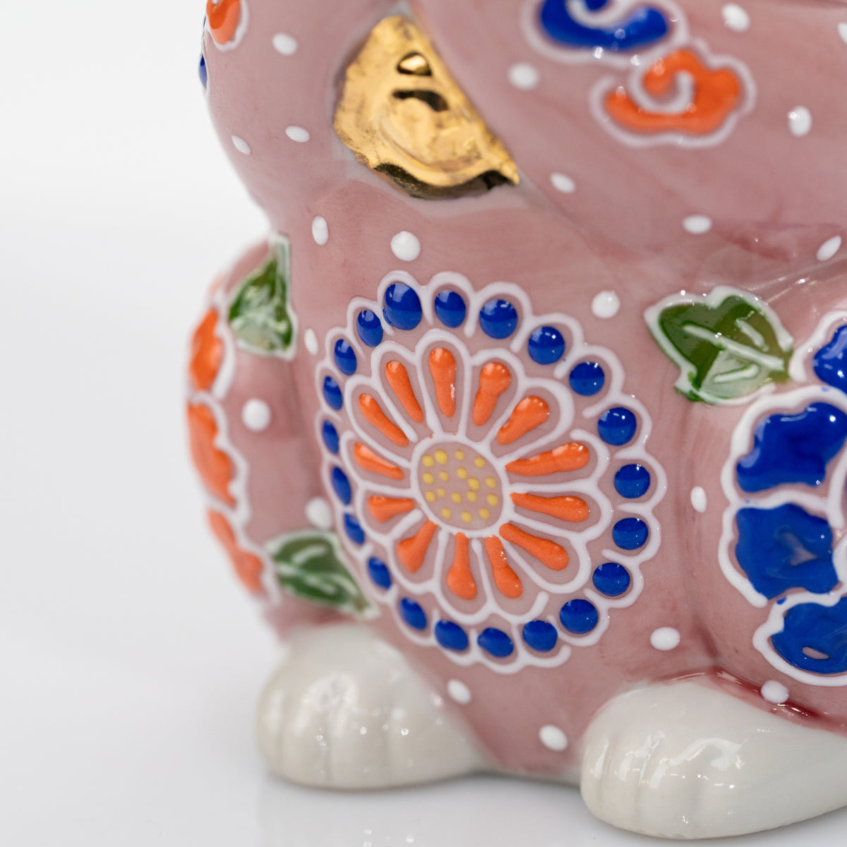 Detail of the front flower with orange petals, cobalt-blue dots, and raised white outlines.