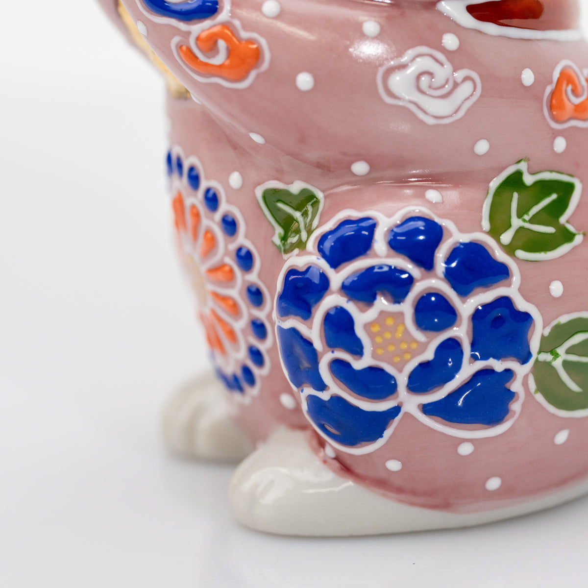Angled close-up of the glossy cobalt-blue flower on the pink ceramic cat.