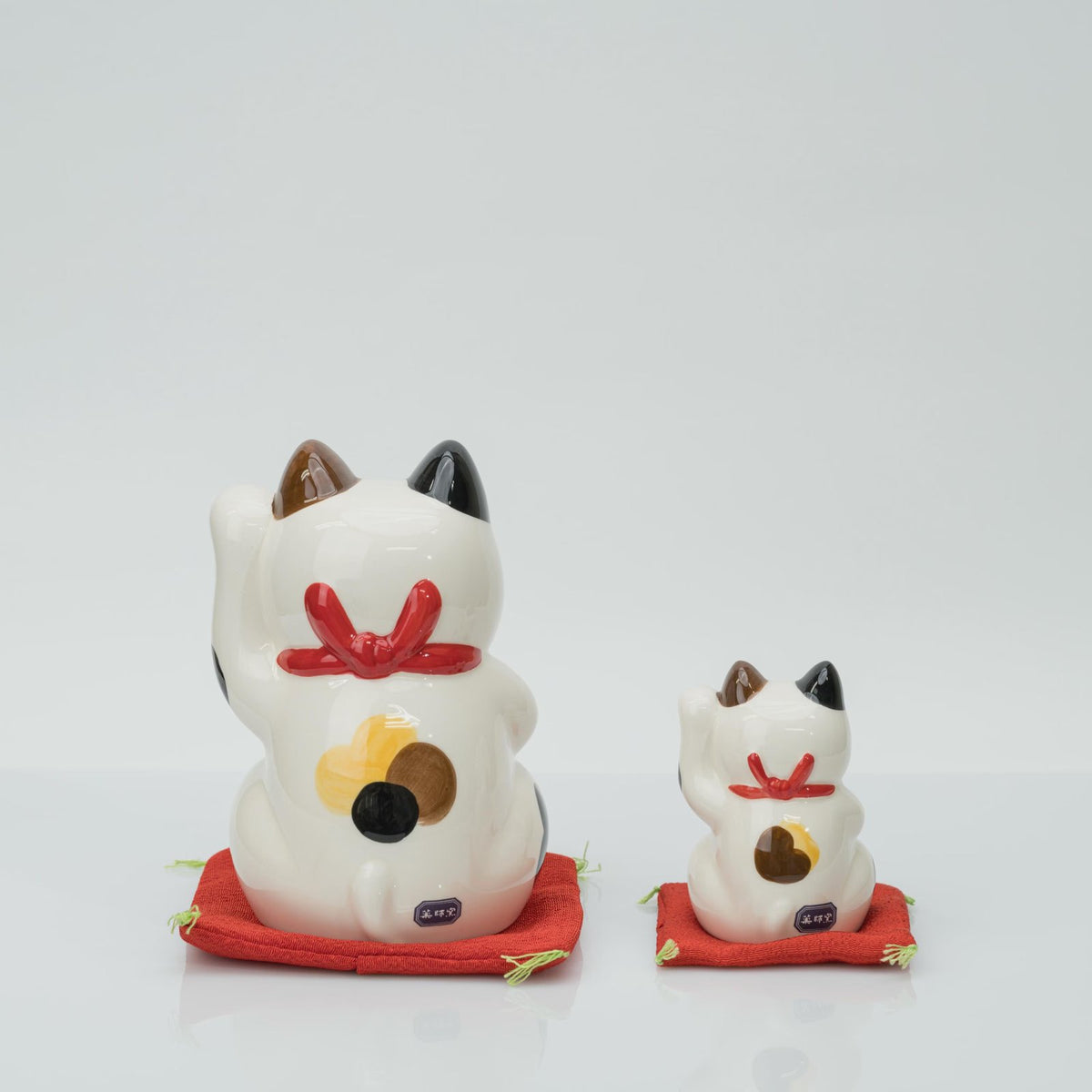 Back view of the 15 cm and 8.5 cm calico lucky cats with red bow collars
