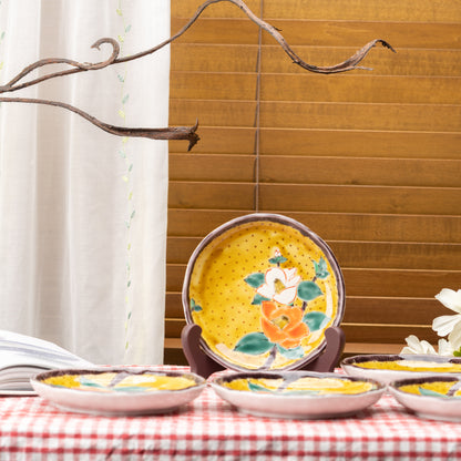 Yellow camellia plates arranged on a red gingham tablecloth, with one plate standing upright behind them.