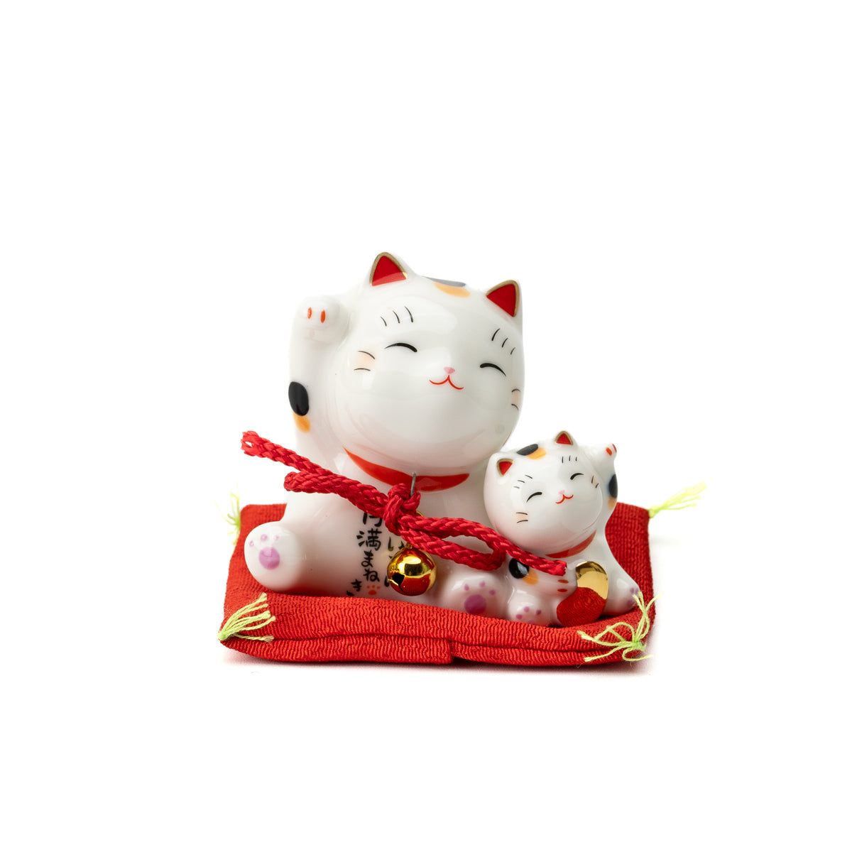 Three-quarter view of a parent-and-kitten lucky cat with red cords on a red display cushion.