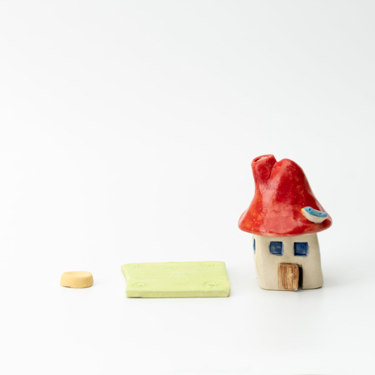 Mushroom house incense burner beside its separate green base and small yellow incense holder.