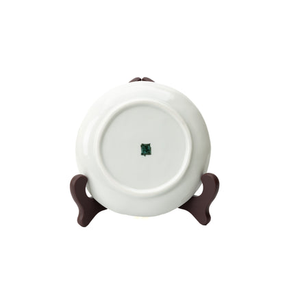 Underside of a white Kutani camellia plate on a stand, showing its circular foot and green maker's mark.