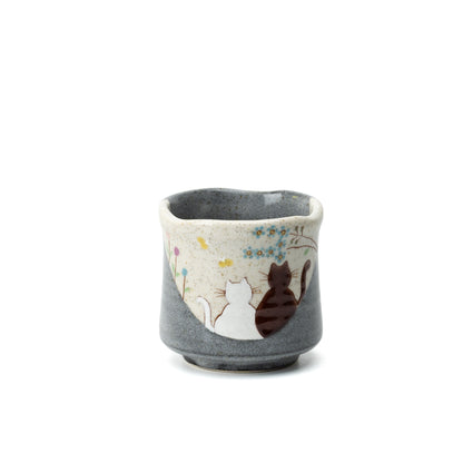 Gray Kutani yunomi with two cats beneath flowering branches, shown on a white background.
