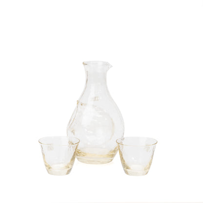 Angled view of the glass sake carafe and two cups.