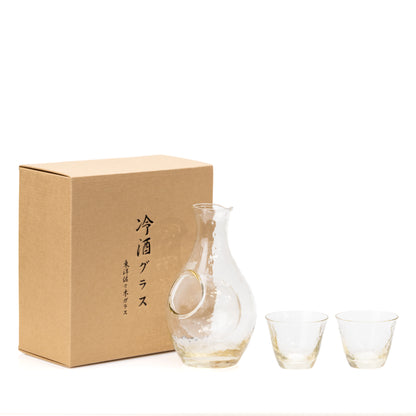 Glass sake carafe and two cups beside their presentation box.