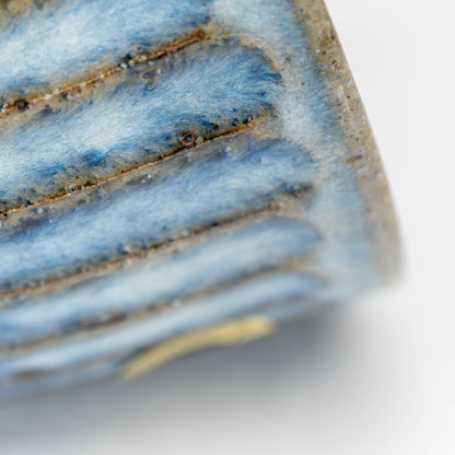 Close-up of blue-gray glaze and brown grooves near the cup's foot.