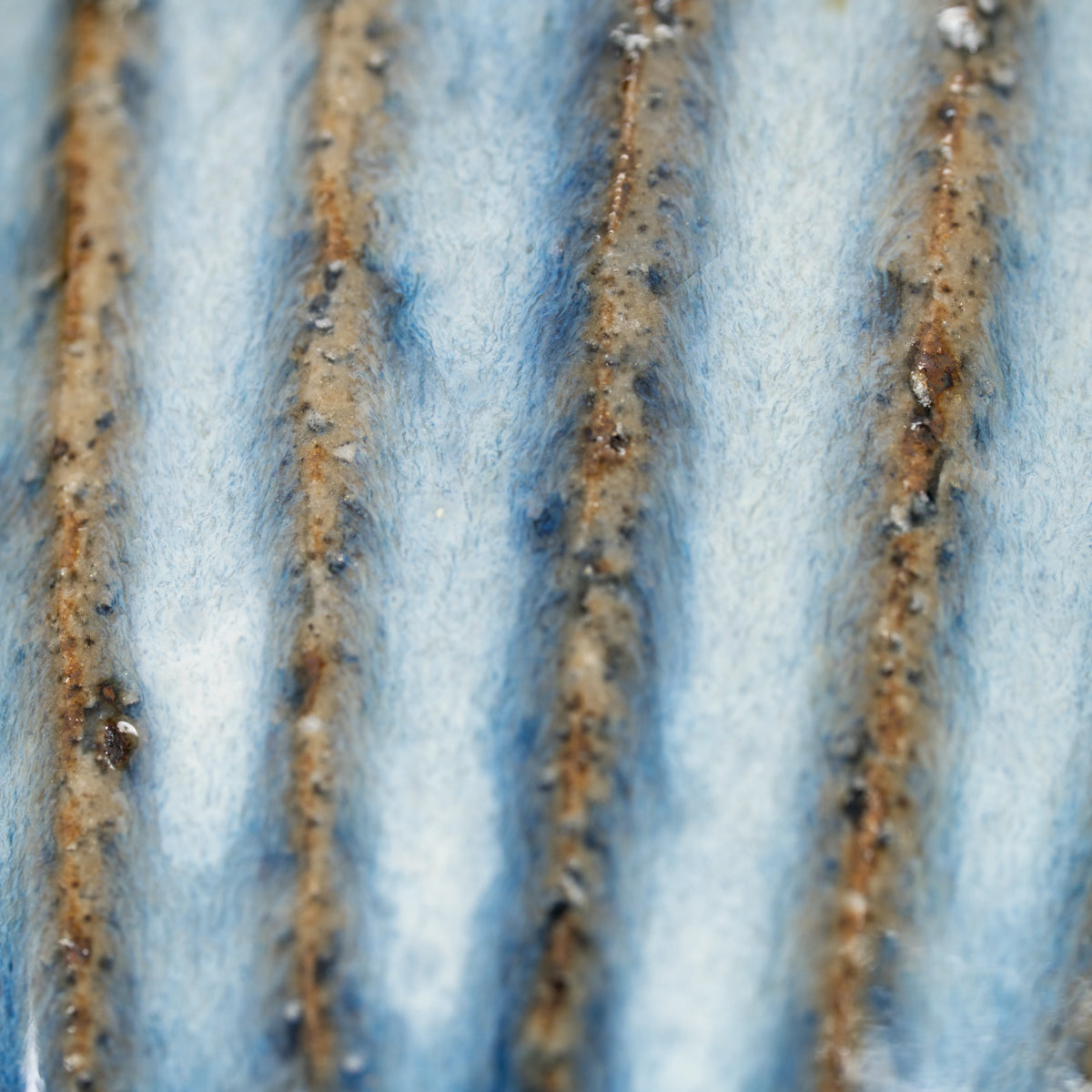 Close-up of long brown grooves in the blue-gray glazed cup.