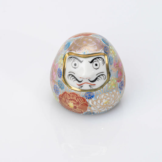 Front view of a blue Kutani porcelain Daruma with a dense multicolored Hanazume floral design and gold-tone outlines