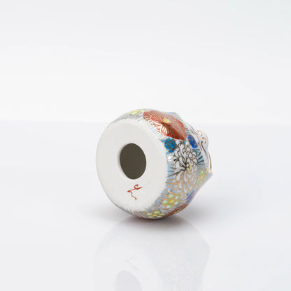 Underside of the Kutani Daruma showing the hollow circular base opening and a red mark