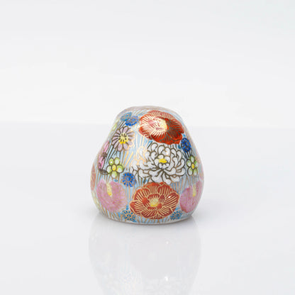 Rear view of the blue Kutani Daruma fully covered with multicolored Hanazume floral decoration
