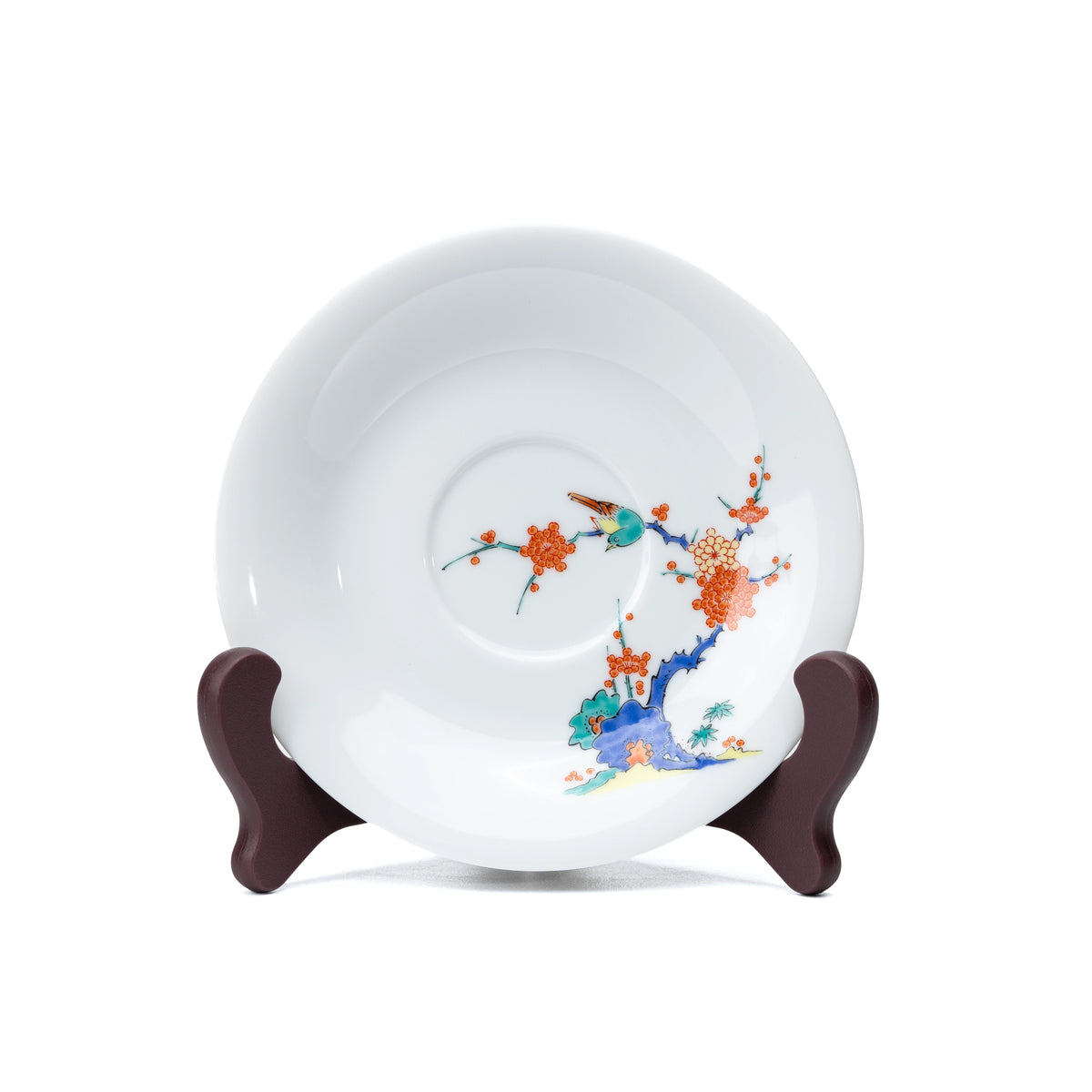 White porcelain saucer with plum blossoms and a bird, viewed from above.