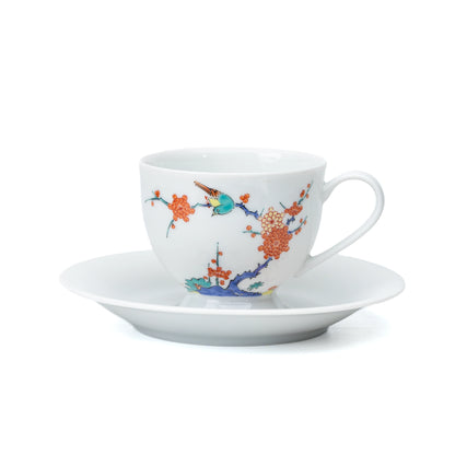White porcelain cup and saucer with plum blossoms and a bird on white.