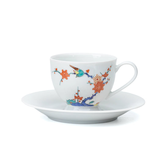 White porcelain cup and saucer with plum blossoms and a bird on white.