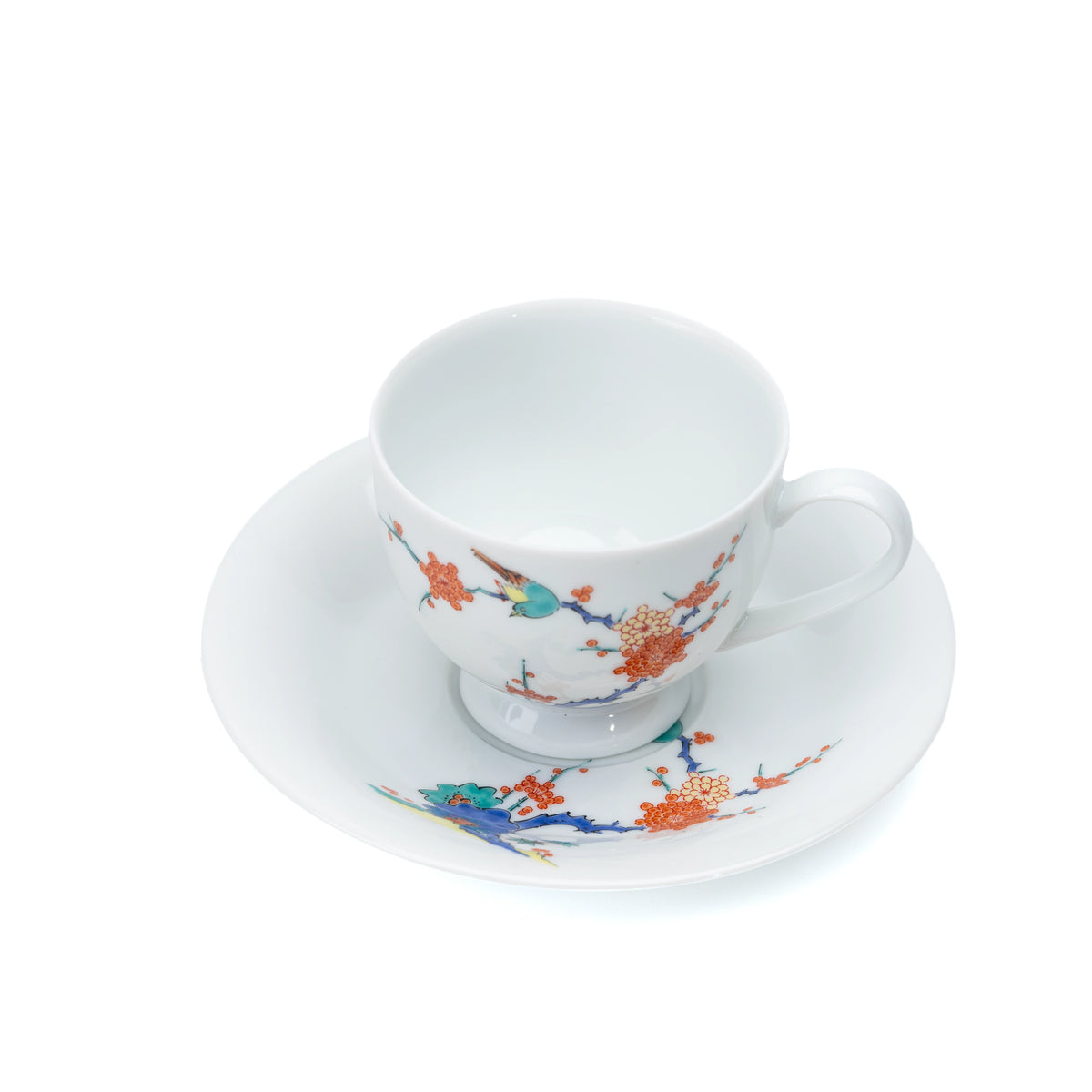 Overhead view of the porcelain cup and saucer with plum blossoms and a bird.