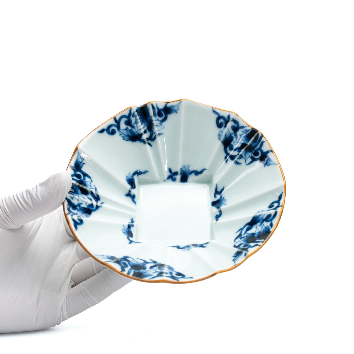 Blue and white scalloped bowl held in a gloved hand.
