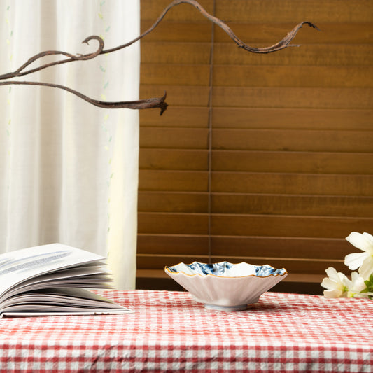 Blue and white bowl on a red checked tablecloth beside a book.
