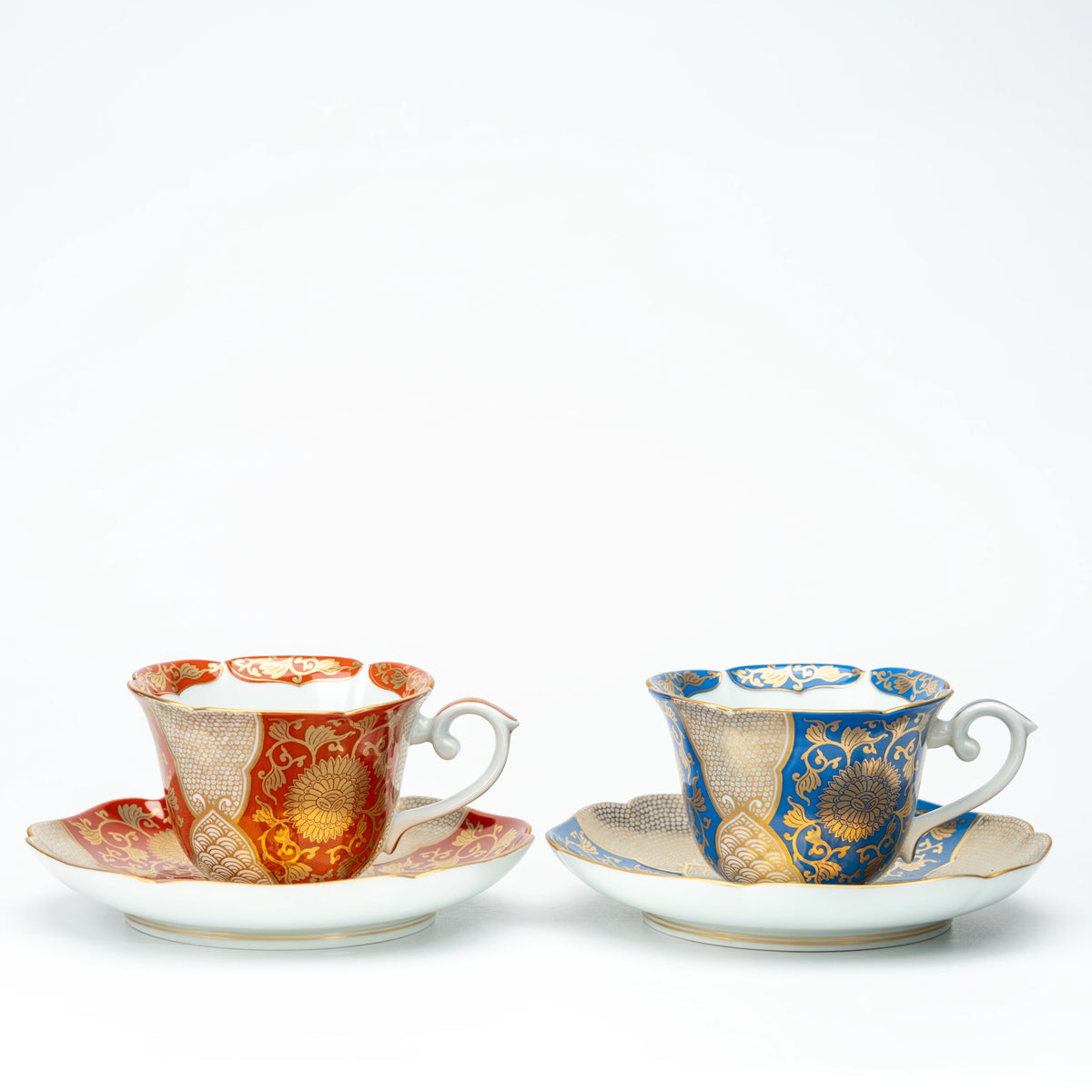 Red and blue versions of the gold-patterned cup and saucer shown side by side for comparison.