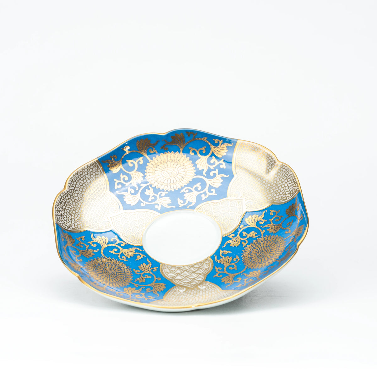 Blue and gold scalloped saucer viewed from above.