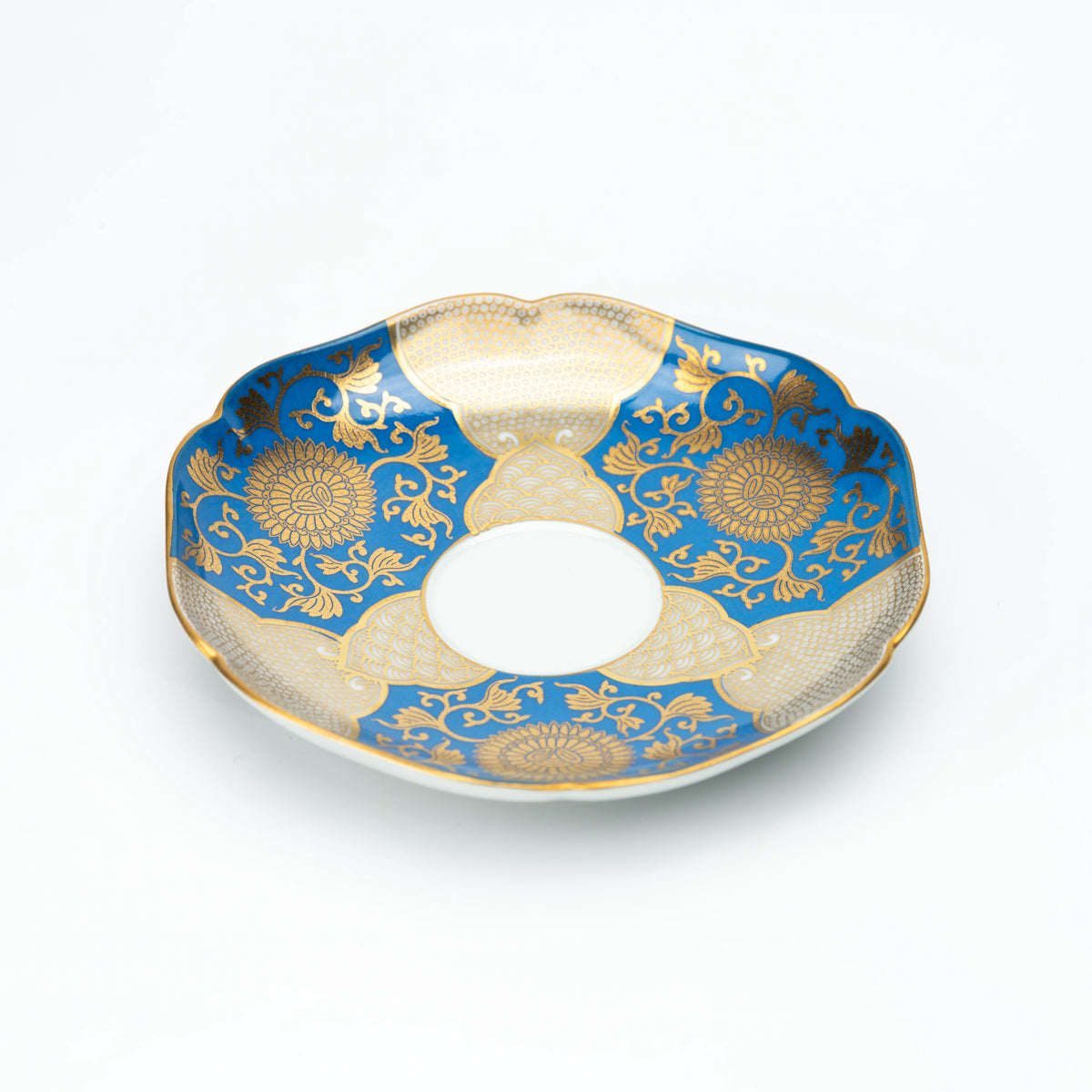 Angled view of the blue and gold scalloped saucer.