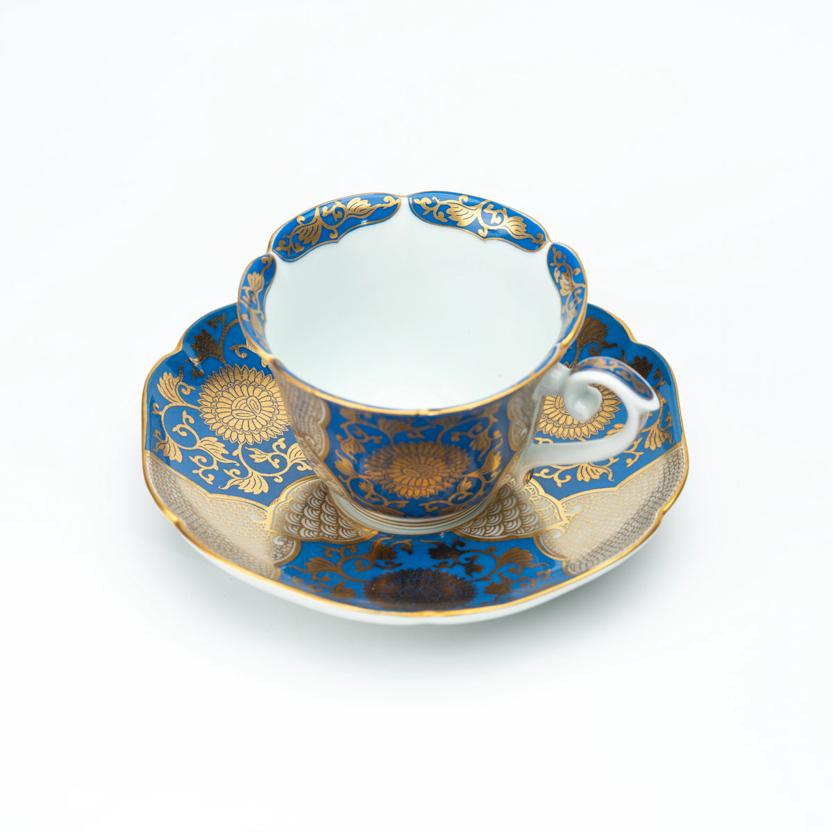 Blue and gold chrysanthemum cup and matching scalloped saucer on white.
