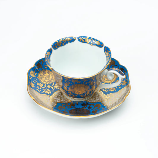 Blue and gold chrysanthemum cup and matching scalloped saucer on white.
