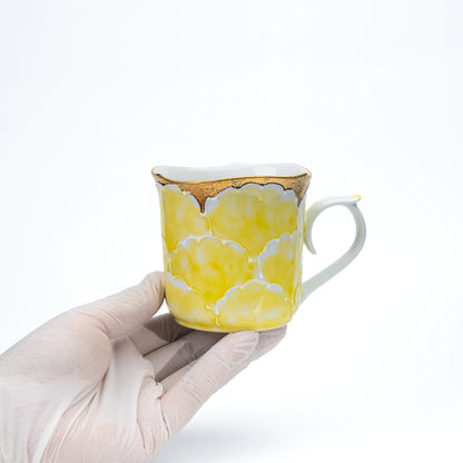 Yellow peony mug held in a gloved hand.