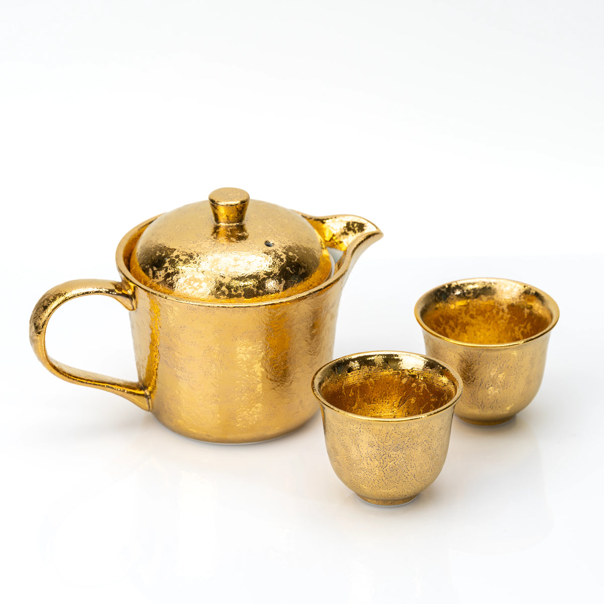 Angled view of the gold teapot and two cups.