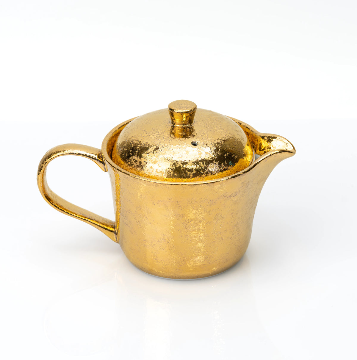 Side view of the gold-glazed teapot and curved handle.