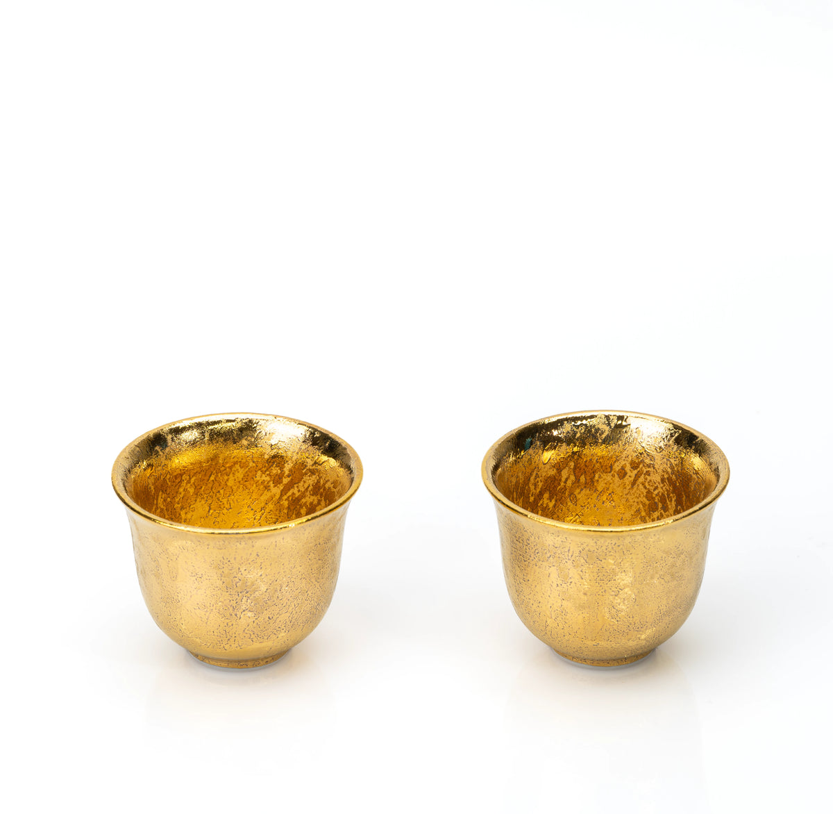Two small gold-glazed cups on white.
