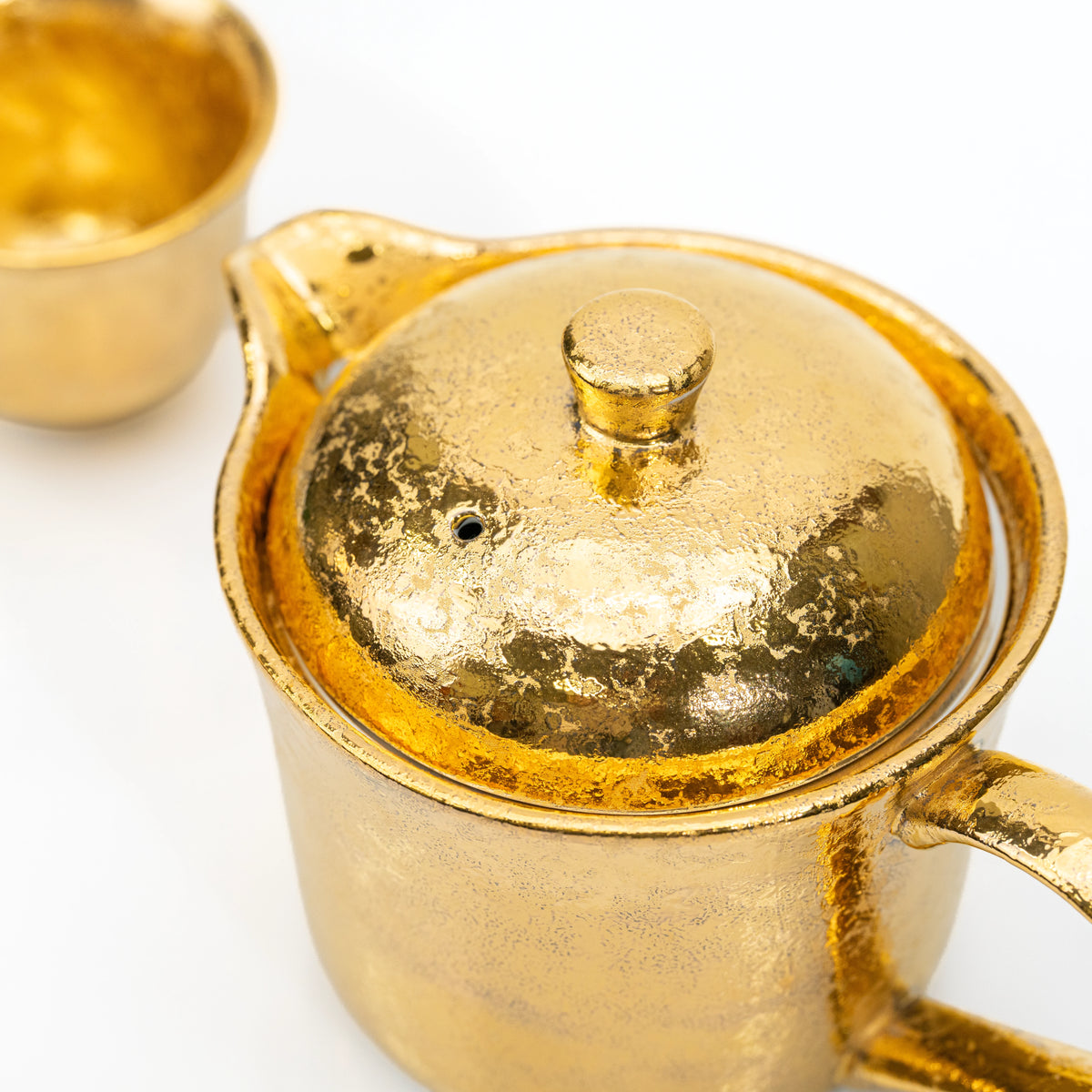 Overhead close-up of the gold teapot lid and knob.