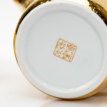 White underside of the gold teapot with a gold maker's mark.