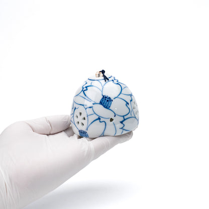 Camellia porcelain wind chime held in a gloved hand.