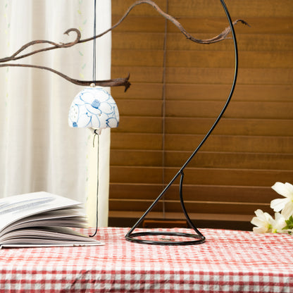 Camellia wind chime hanging from a display stand on a red checked tablecloth.