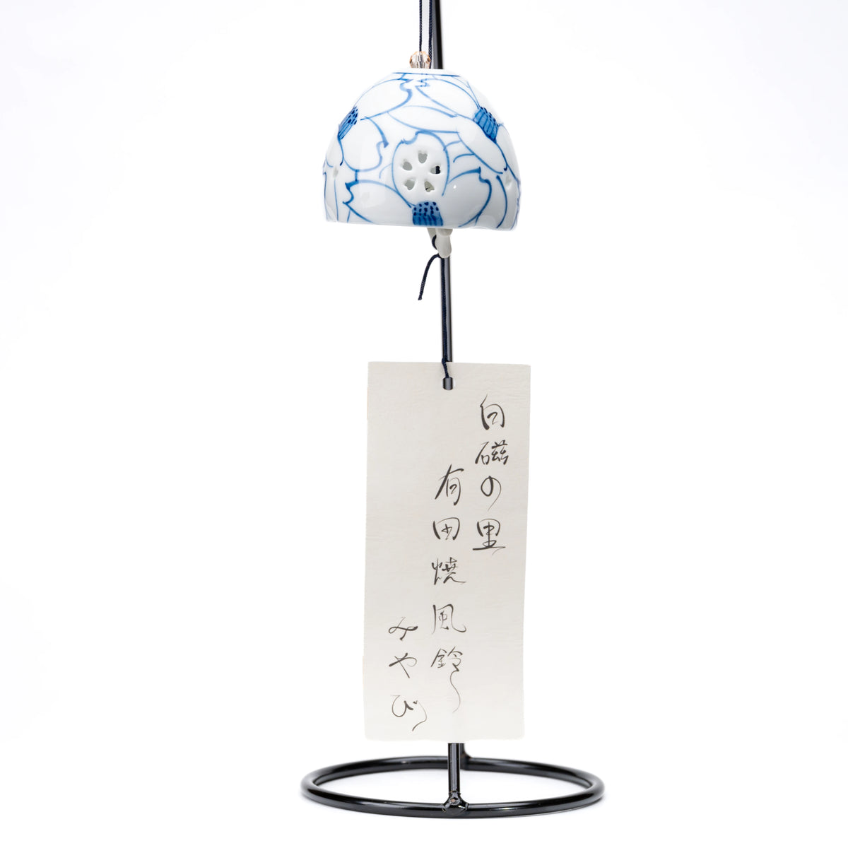 Camellia porcelain wind chime and paper strip hanging from a black display stand on white.