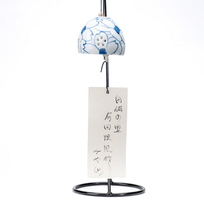 Camellia porcelain wind chime and paper strip hanging from a black display stand on white.