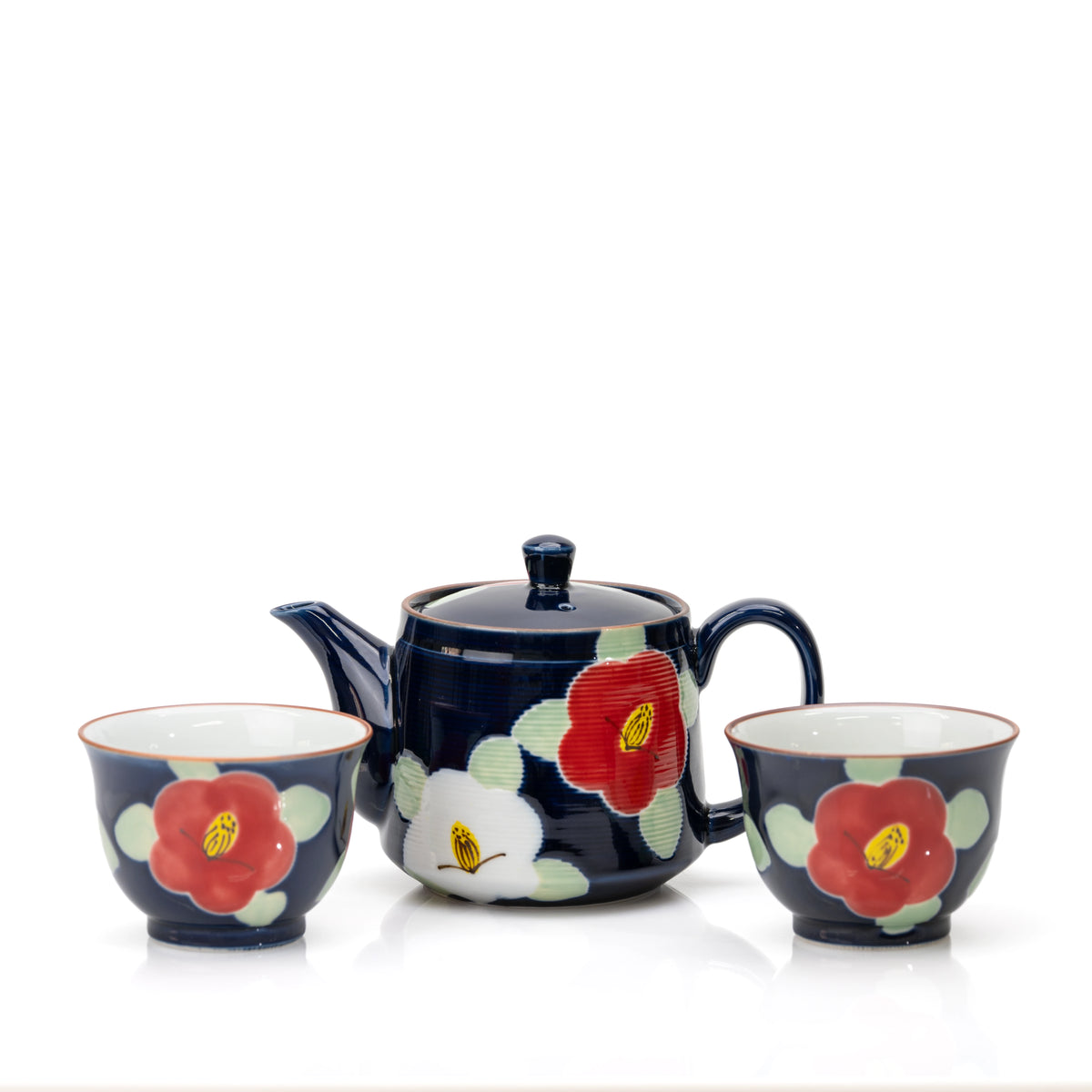 Deep blue camellia teapot and two matching cups with red and white flowers on white.