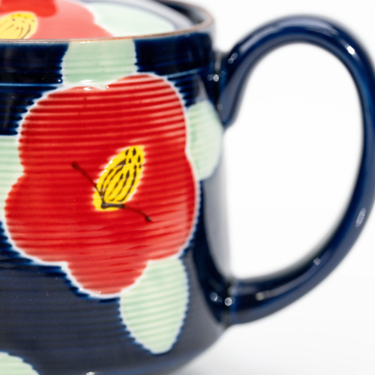 Handle and red camellia decoration on the blue teapot.
