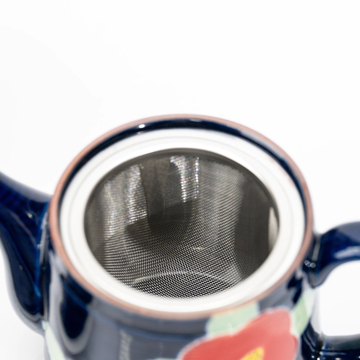 Top view into the blue teapot and its metal mesh strainer.