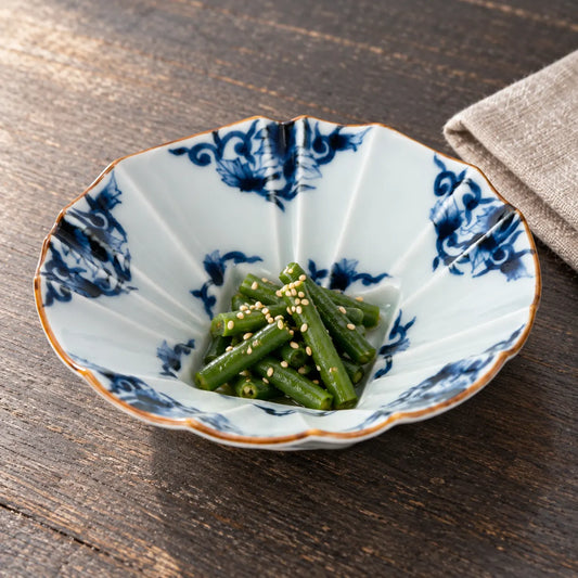 A shallow blue-and-white karakusa bowl with faceted sides, holding a small serving of sesame-dressed green beans