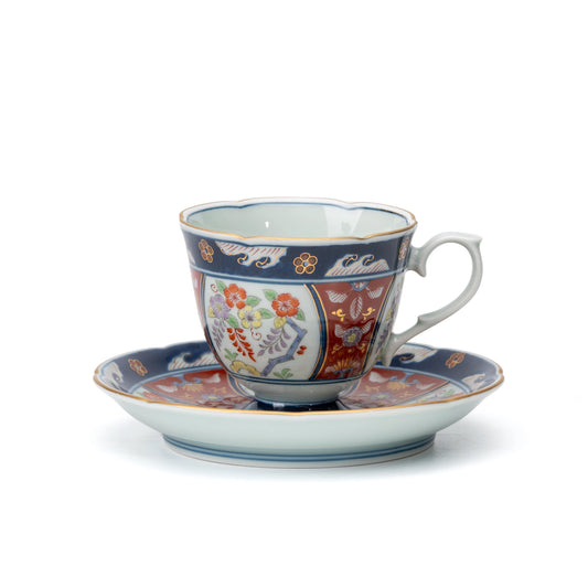 Blue and red Arita cup and saucer with floral panels and gold accents on white.