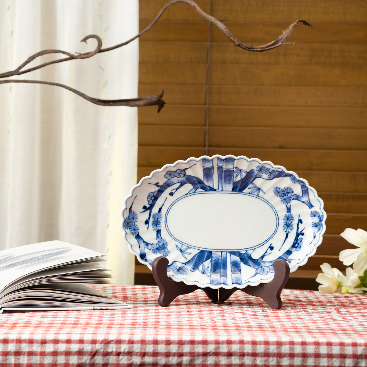 Blue and white oval platter displayed on a stand on a red checked tablecloth.