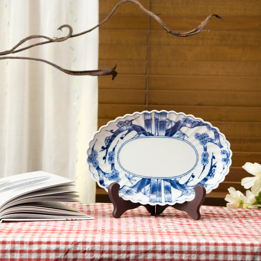 Blue and white oval platter displayed on a stand on a red checked tablecloth.