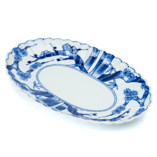 Blue and white oval porcelain platter with scalloped edges and landscape panels on white.