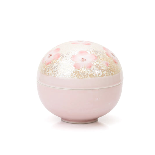 Round pink porcelain lidded bowl with cherry blossoms and pale textured decoration on white.