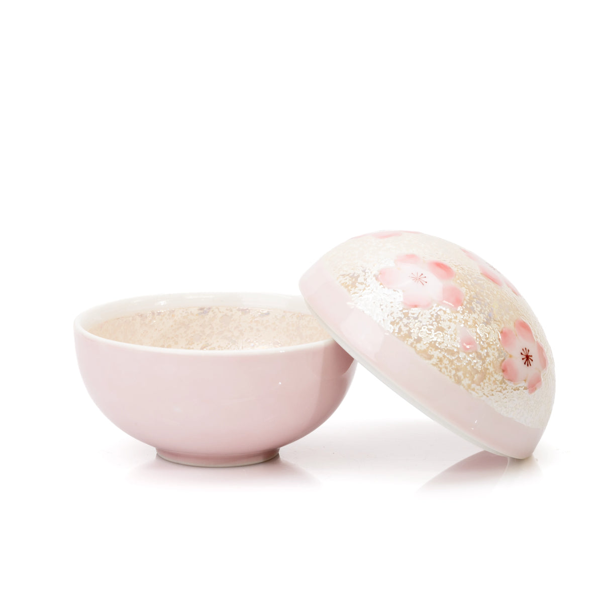 Pink bowl with its domed cherry blossom lid resting beside it.