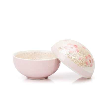 Pink bowl with its domed cherry blossom lid resting beside it.