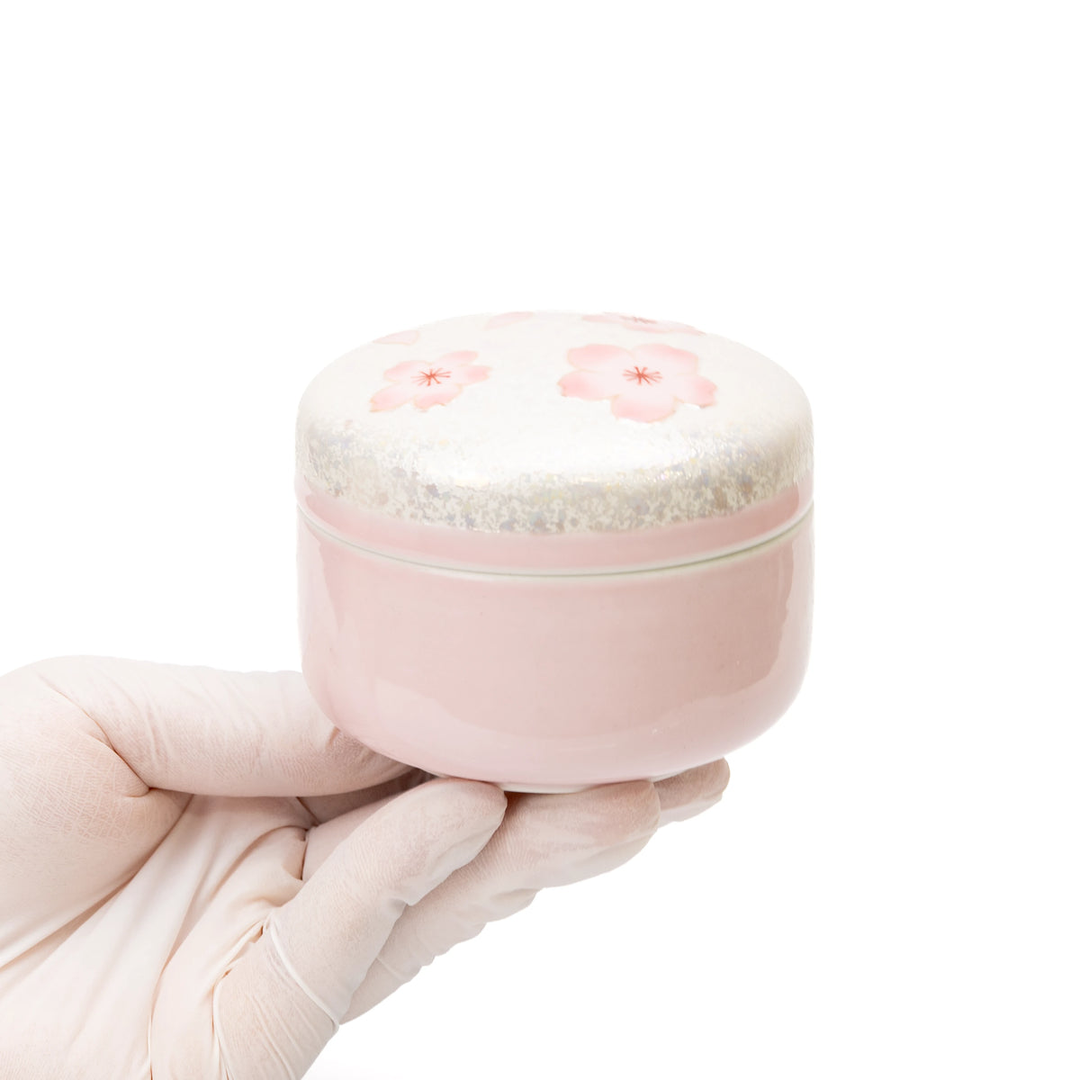 Pink cherry blossom lidded box held in a gloved hand.