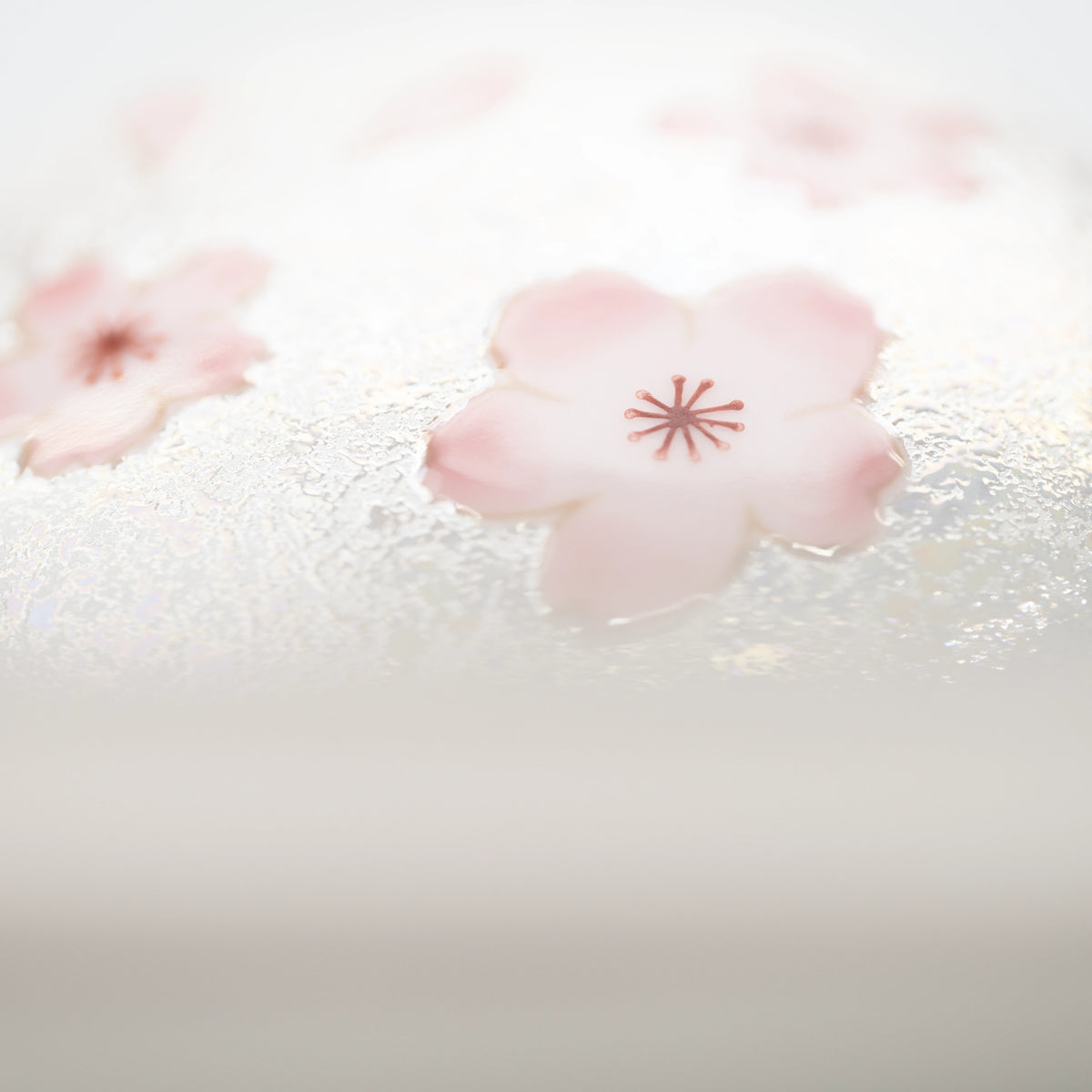 Detail of the lid's rounded edge and pink floral decoration.