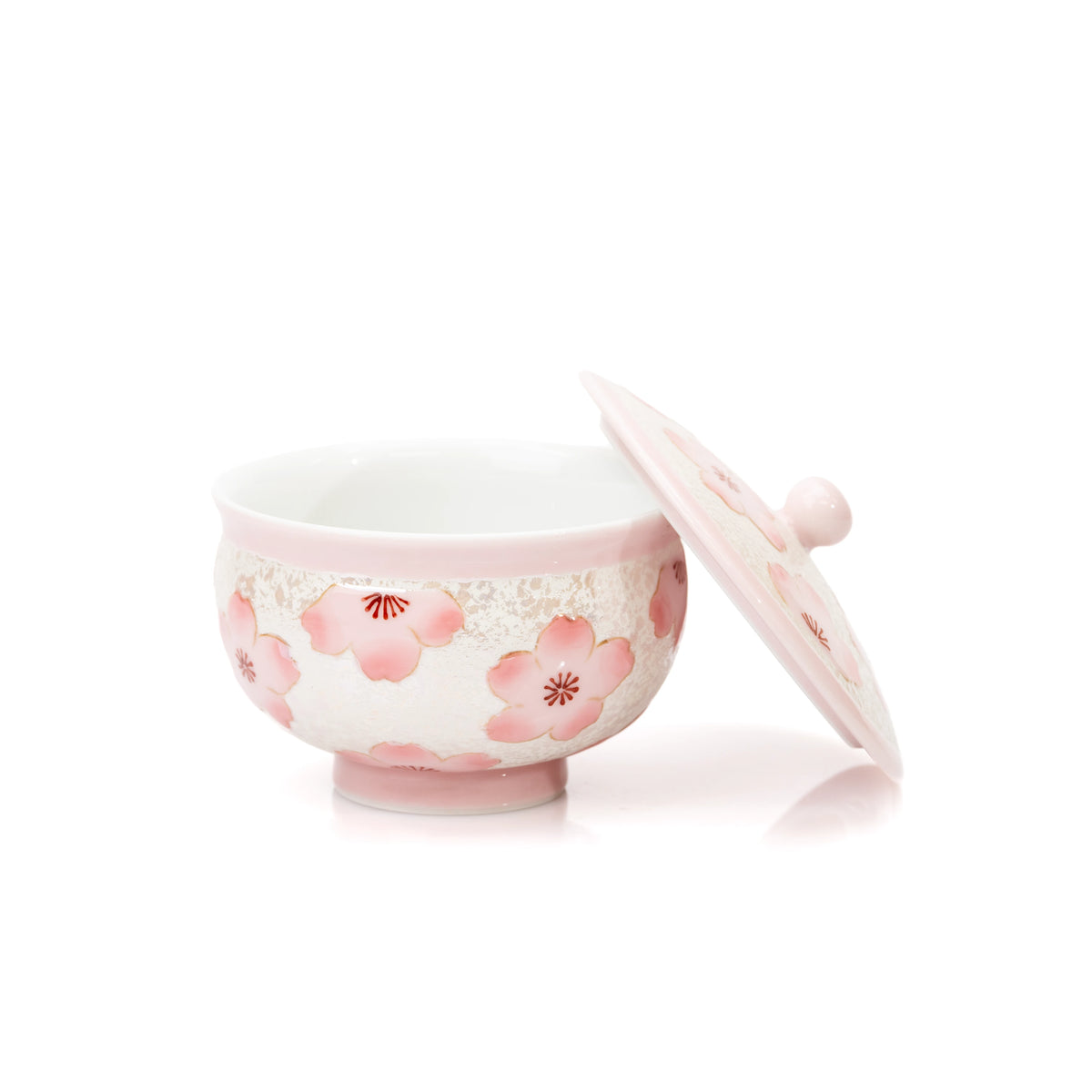 Pink teacup with its cherry blossom lid leaning beside it.